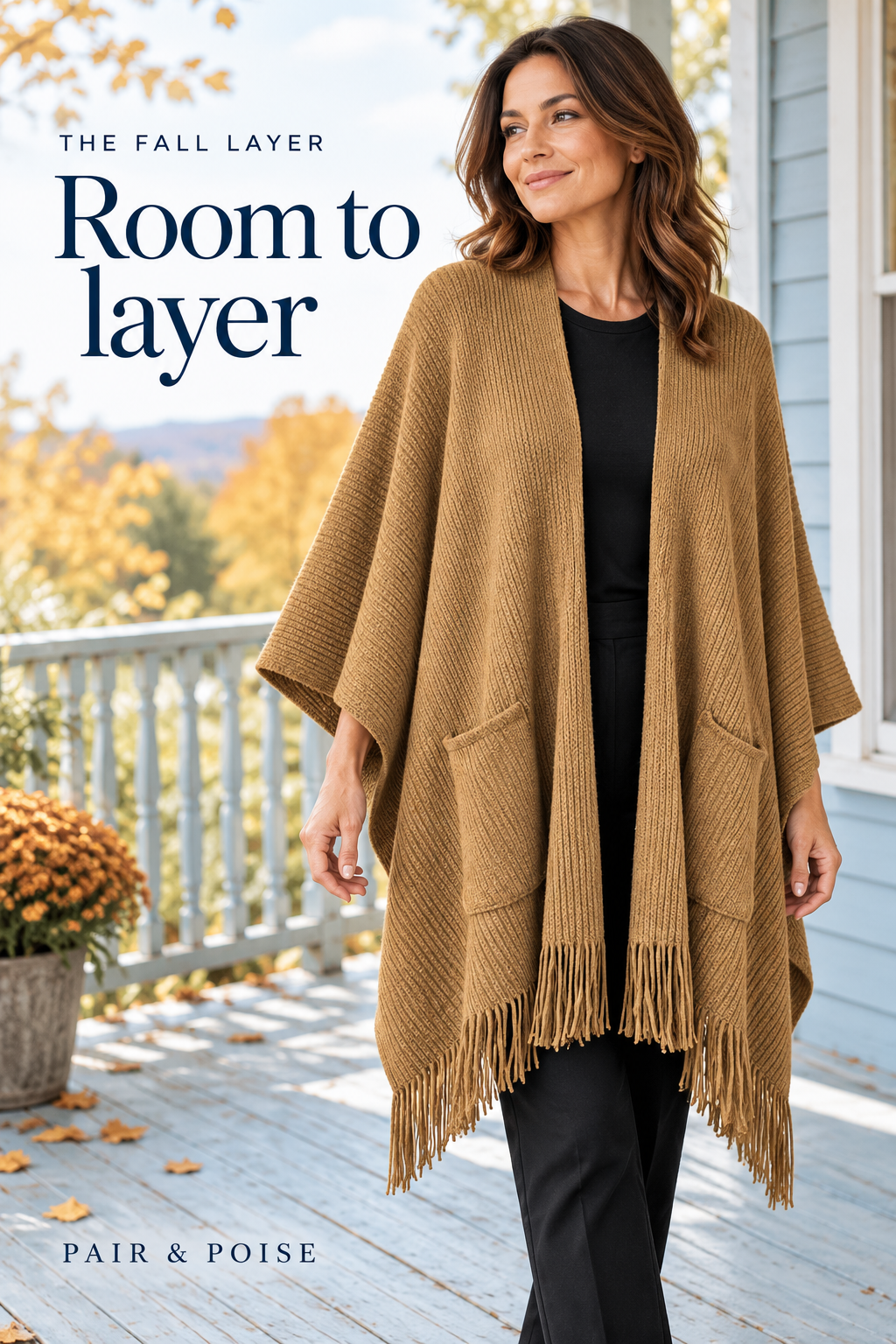 Fictional adult woman on a pale-blue porch wearing a camel open-front ribbed poncho with two patch pockets, wide sides and a fringed hem over plain black base clothes.